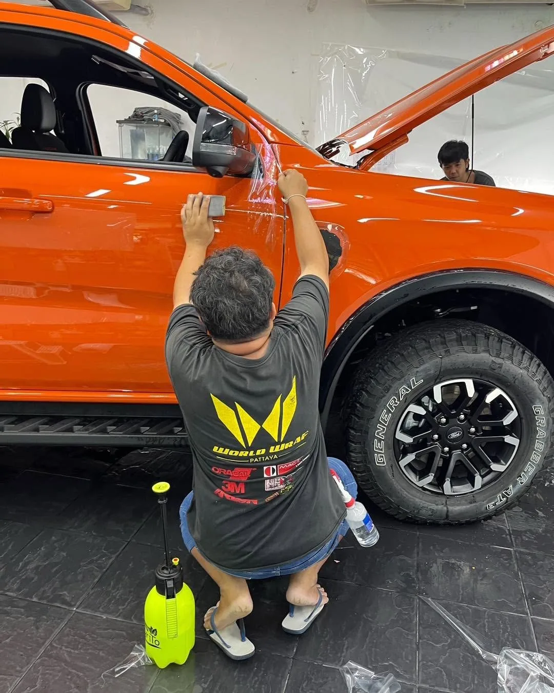 ช่างติดตั้งฟิล์มใสบน SUV สีส้ม