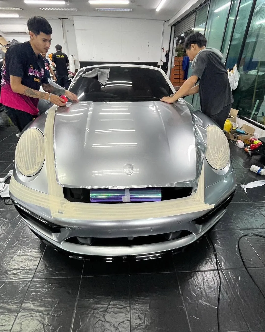 ช่างกำลังติดตั้งฟิล์มใสกันรอยบน Porsche 911 สีเงิน